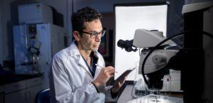 Researcher taking notes on a microscope specimen