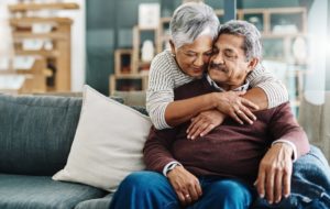 Woman hugging husband sitting on couch