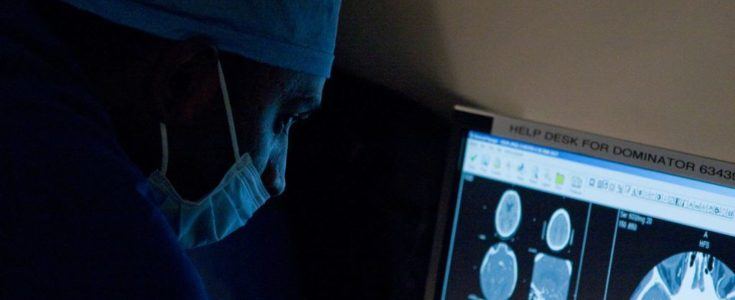 Surgeon looking at brain scans on a screen