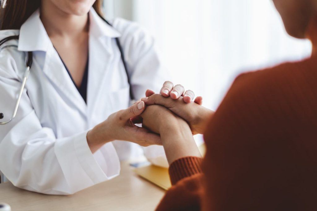 a doctor holding her patients hands