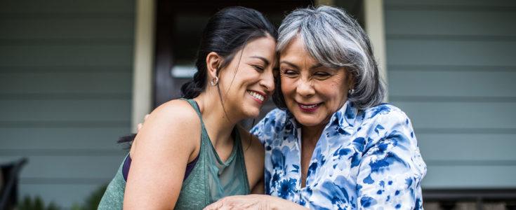 Senior woman and adult daughter laughing on porch