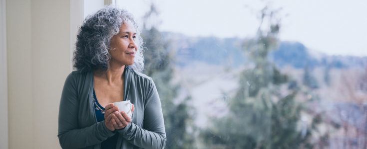 Mature woman standing with coffee cup looking into the distance