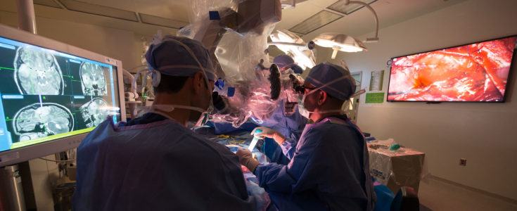 Active surgery room with displays of brain scans.