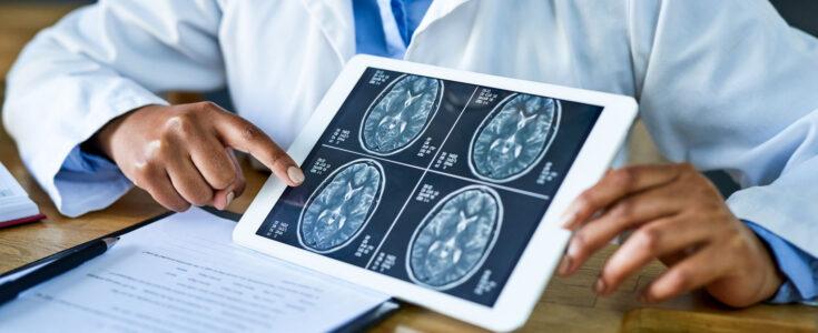 Shot of a doctor using a digital tablet to discuss a brain scan during a consultation in her office.