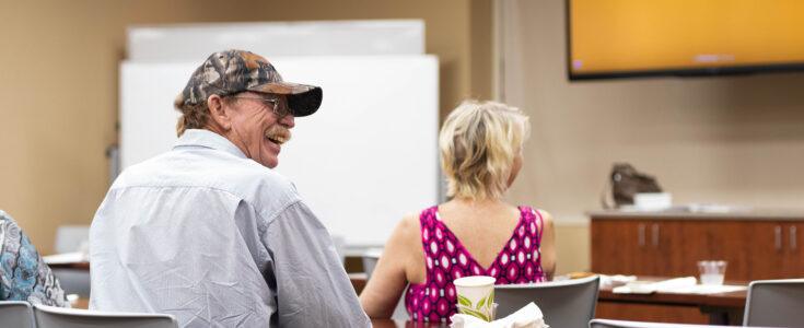 Smiling man and woman with her back turned during a patient brain tumor support group at Barrow.